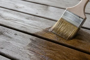 Application d'une solution éclaircissante sur des planches de terrasse en bois grisé au pinceau