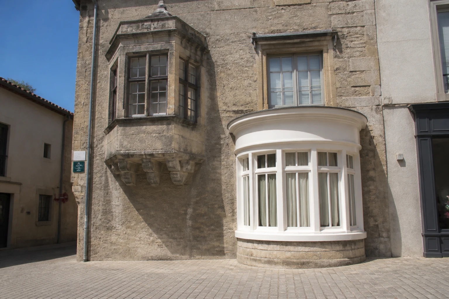 Façade avec un oriel en pierre au premier étage et un bow-window arrondi au rez-de-chaussée