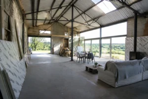 Hangar en cours de transformation en maison habitable avec structure métallique apparente et fenêtres