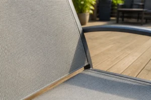 Chaise de jardin en textilène gris clair sur terrasse en bois, texture toile PVC visible en gros plan