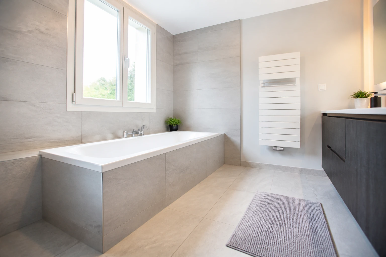 Baignoire encastrée blanche vue de profil dans une salle de bains moderne, hauteur de rebord visible