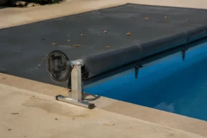 Bâche à barres partiellement enroulée au bord d'une piscine rectangulaire avec terrasse béton
