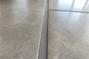 Joint de dilatation souple entre deux rangées de carrelage en grès gris sur sol intérieur