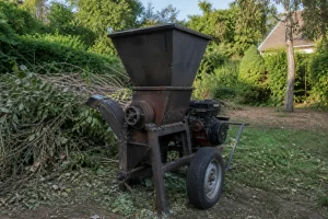 Broyeur de végétaux maison en métal avec trémie et châssis sur roues dans un jardin