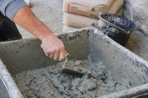 Artisan gâchant du mortier à la truelle dans une auge sur un chantier de rénovation
